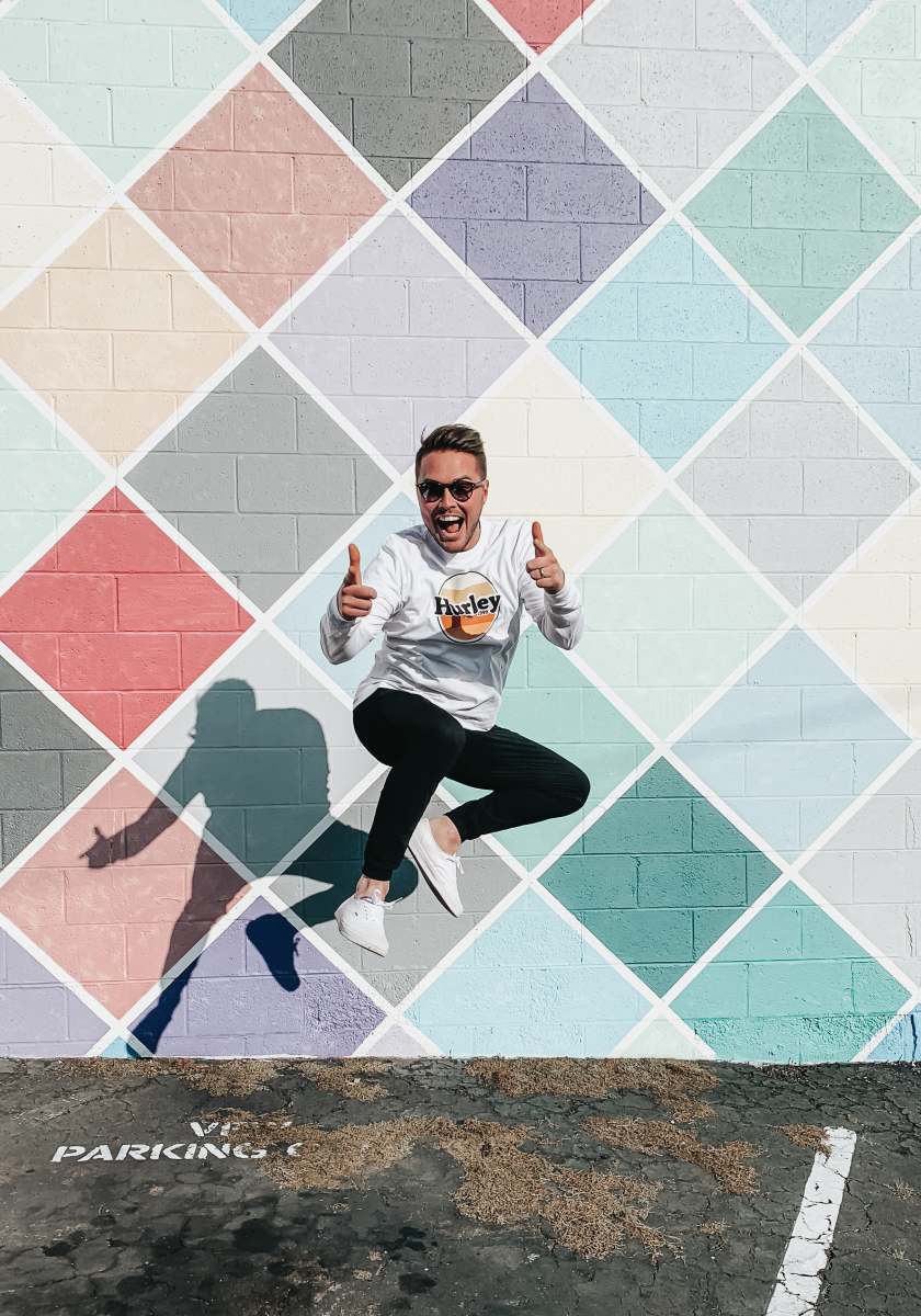 san diego man in white and orange crew neck t-shirt and black pants sitting on blue and ca
